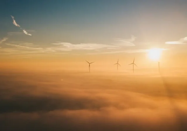 Wind turbines poking through the clouds.